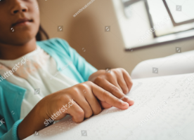 Picture of a blind kid reading a braille book.