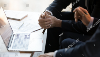 Picture of two men having a discussion sitting in front of a laptop.